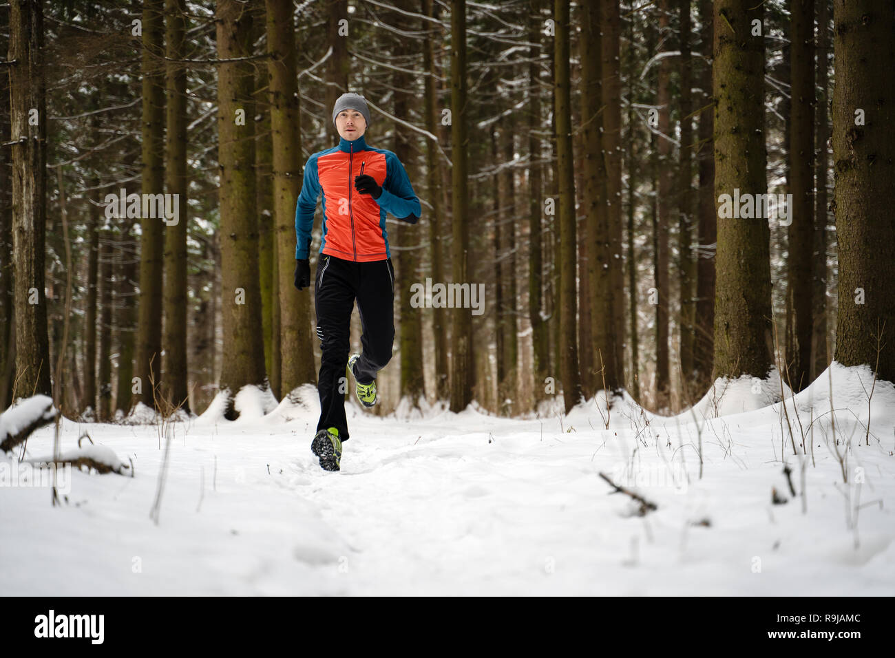 Photo de l'athlète d'exécution entre les arbres en forêt d'hiver Banque D'Images