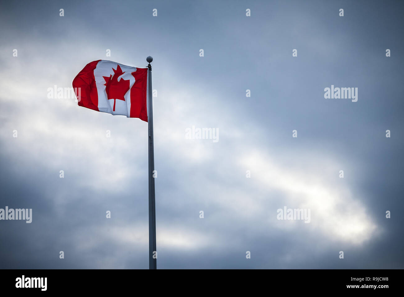 Drapeau canadien, avec sa célèbre feuille d'érable rouge, la suppression dans l'air sur un poteau, outoors, lors d'un après-midi pluvieux nuageux à Ottawa, Canada Photo de th Banque D'Images