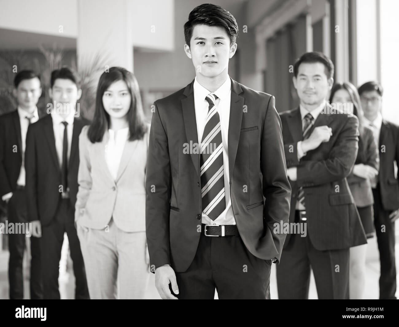 Portrait d'une équipe d'hommes et de femmes d'affaires asiatiques, looking at camera, noir et blanc. Banque D'Images