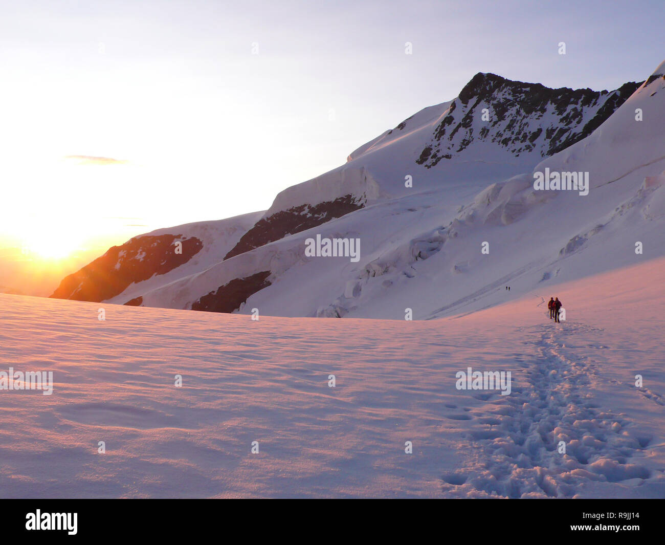 D'alpiniste sur une corde de marcher à travers un grand glacier dans les Alpes Suisses juste après le lever du soleil Banque D'Images