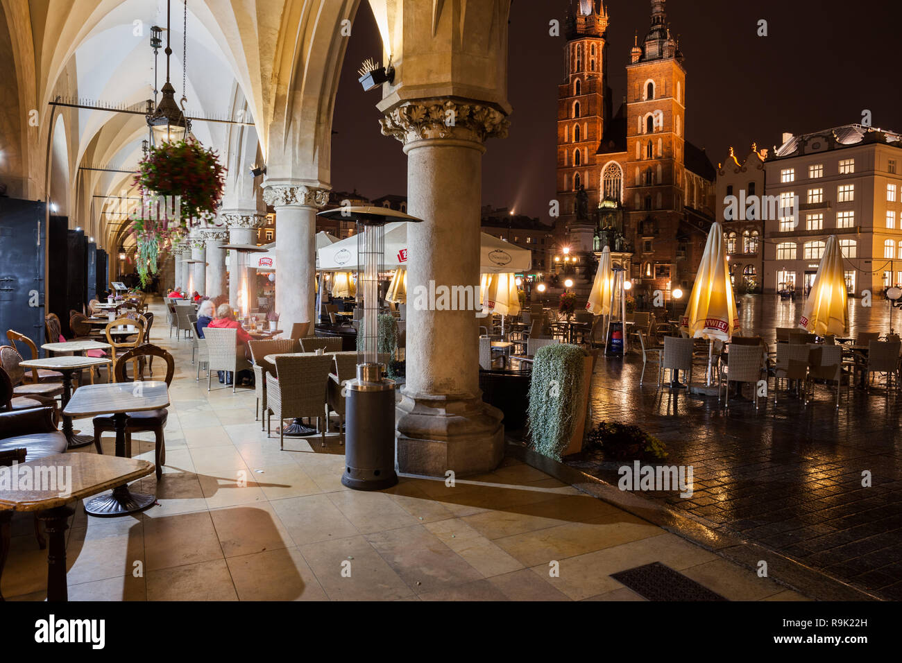 Café en plein air dans les tables de nuit de la ville de Cracovie en Pologne, vue de l'arcade de la salle (Coth Sukiennice) à l'église Sainte Marie sur la place principale dans le Banque D'Images