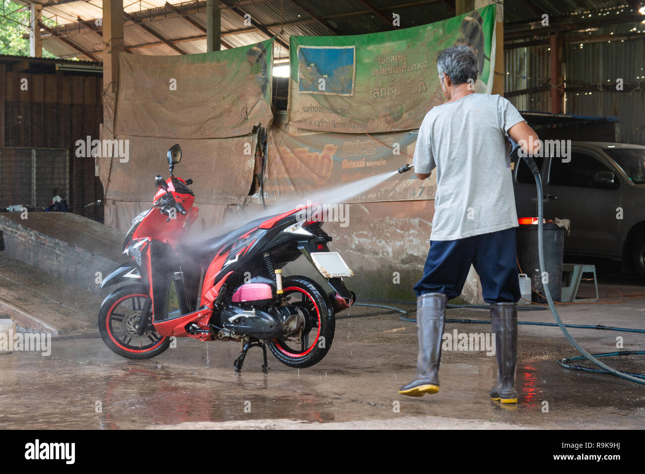 Vieil homme laver votre moto avec nettoyeur haute pression au lavage de  voiture shop Photo Stock - Alamy