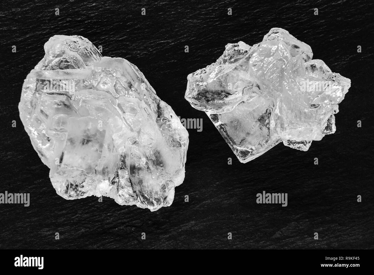 Vue de dessus deux sucre ou sel cristaux placés sur la surface de base en pierre noire Banque D'Images