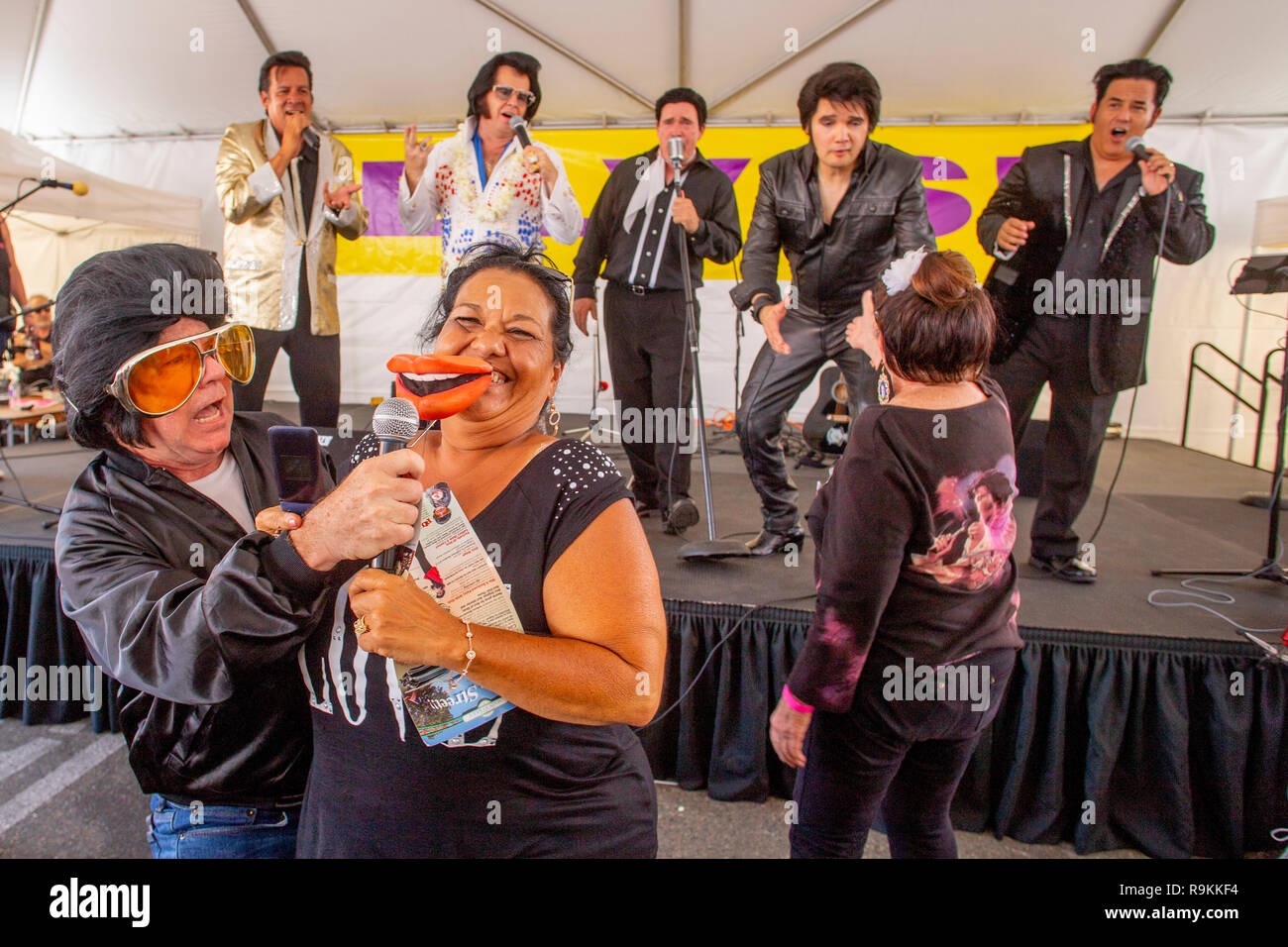 Un groupe d'imitateurs d'Elvis Presley concurrentes confèrent d'énormes lèvres jouer sur un portrait du ventilateur à un festival de musique tente de Fullerton, CA. Banque D'Images
