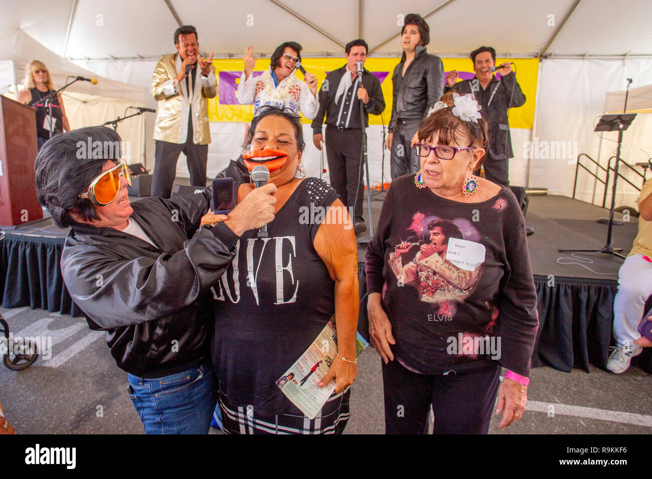 Un groupe d'imitateurs d'Elvis Presley concurrentes confèrent d'énormes lèvres jouer sur un portrait du ventilateur à un festival de musique tente de Fullerton, CA. Banque D'Images