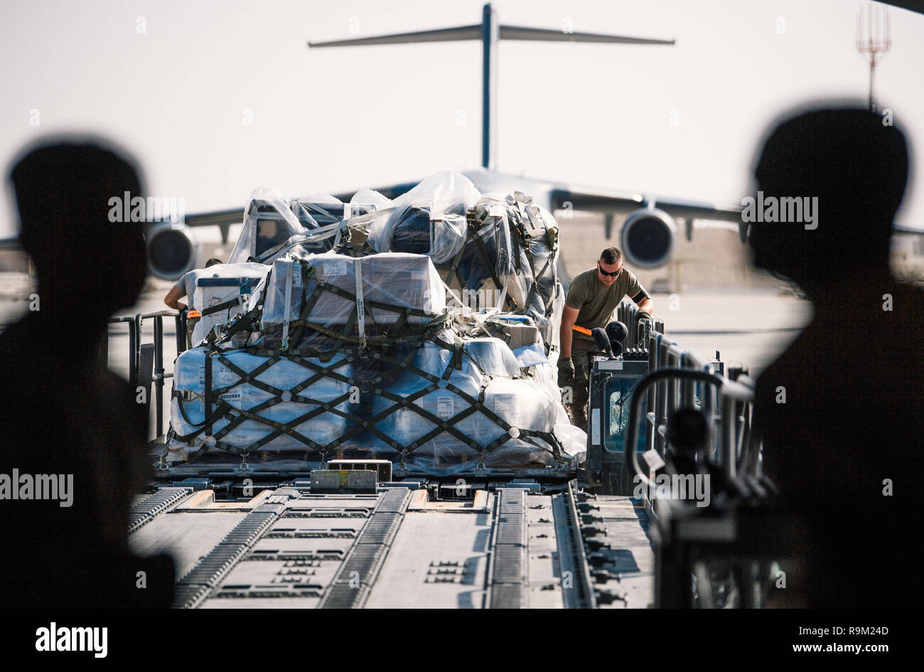 Une 379e Escadron expéditionnaire de préparation logistique fret aérien guides porter chargé sur un véhicule d'assistance au sol vers un corps expéditionnaire 816th Airlift Squadron C-17 Globemaster III à l'appui de l'opération Liberté Sentinel sur Al Udeid Air Base, Qatar, le 7 décembre 2018. 379SEIE porteurs aériens sont responsables de la palettisation et le déplacement de cargaisons sur le sol des Etats-Unis et les forces de la Coalition. (U.S. Photo de l'Armée de l'air par le sergent. La Jordanie Castelan) Banque D'Images