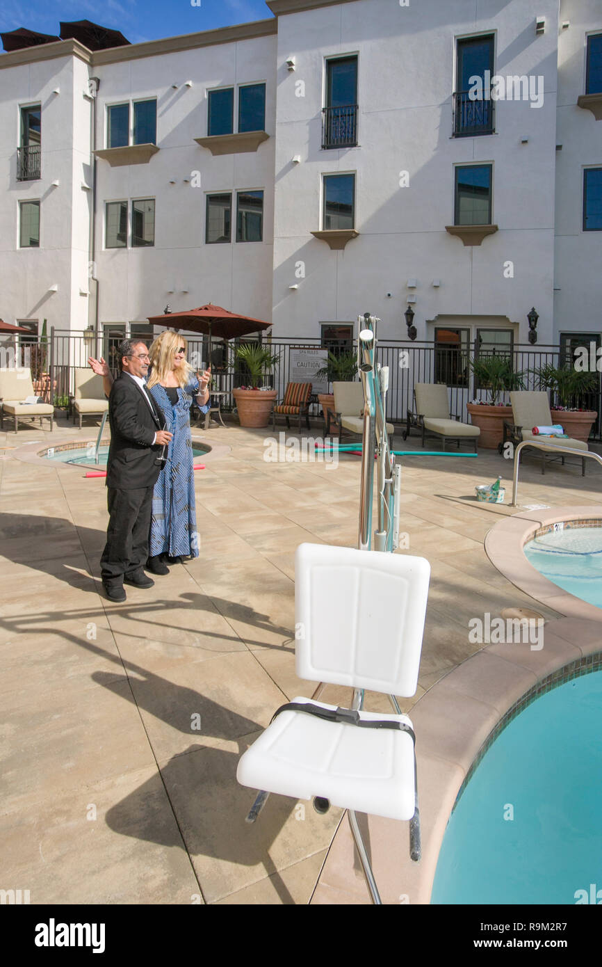 Deux résidents éventuels sur une Laguna Niguel, CA, communauté de retraite plaza inspecter un palan président de la piscine pour accueillir les nageurs handicapés. Banque D'Images