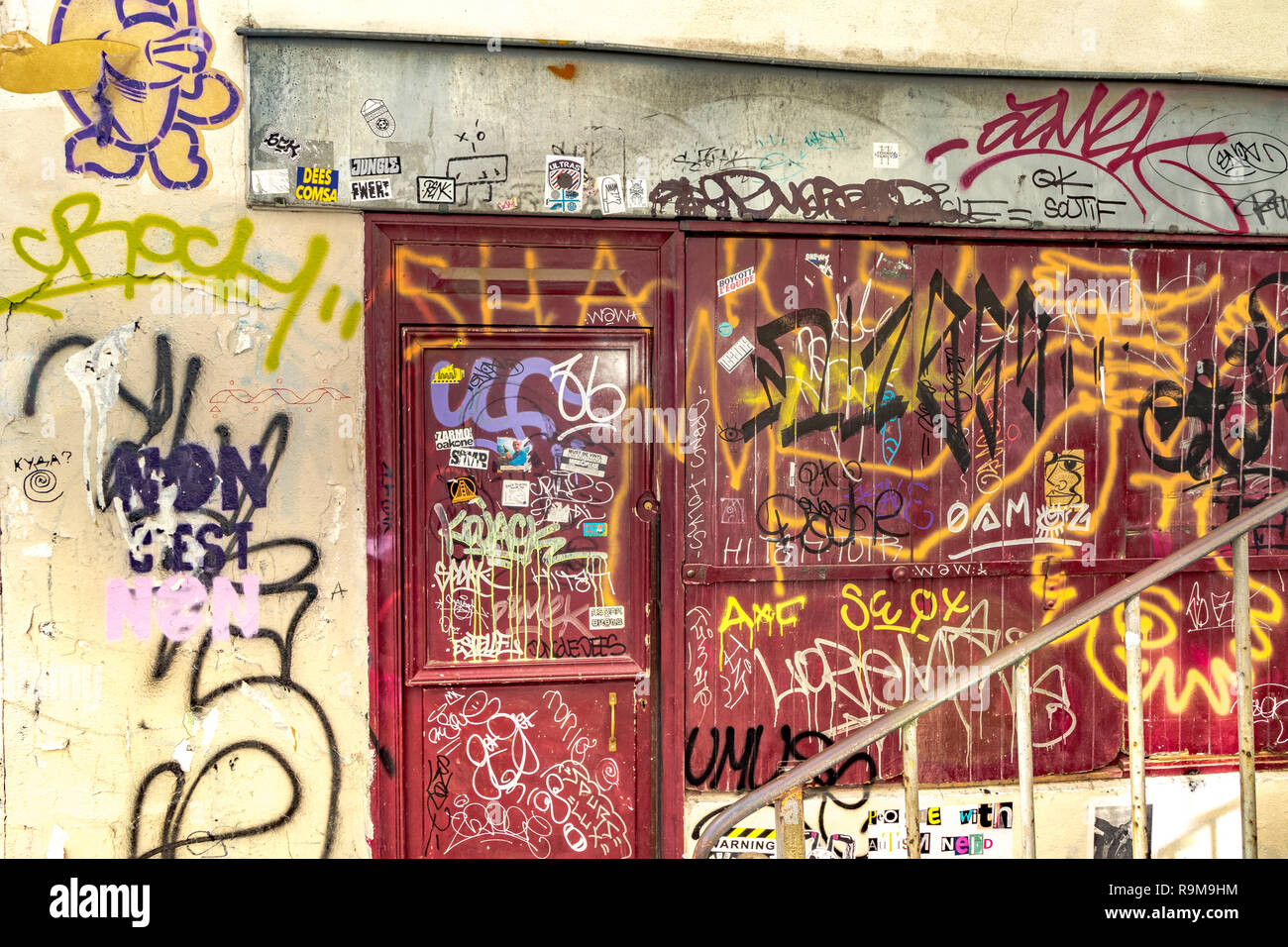 Une porte et une fenêtre rouges arraisonnées recouvertes de graffiti et de peinture aérosol , Montmartre Paris, France Banque D'Images