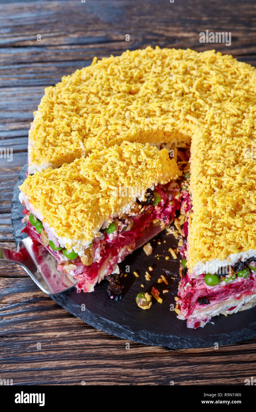Sept Delicieux Gateau En Couches Avec Salade De Legumes œufs Durs Les Pruneaux Les Noix Et La Viande De Poulet Sur Une Plaque Noire Sur Une Vieille Table En Bois Vertical Photo