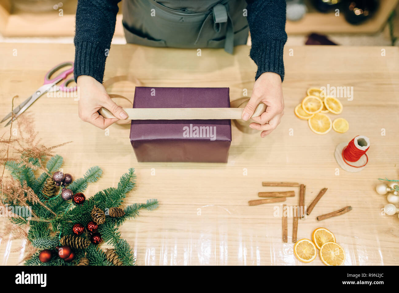 Vendeur femelle décore boîte-cadeau avec du papier d'emballage et ruban d'or, de la décoration. Femme wraps présent sur la table, le décor intérieur Banque D'Images