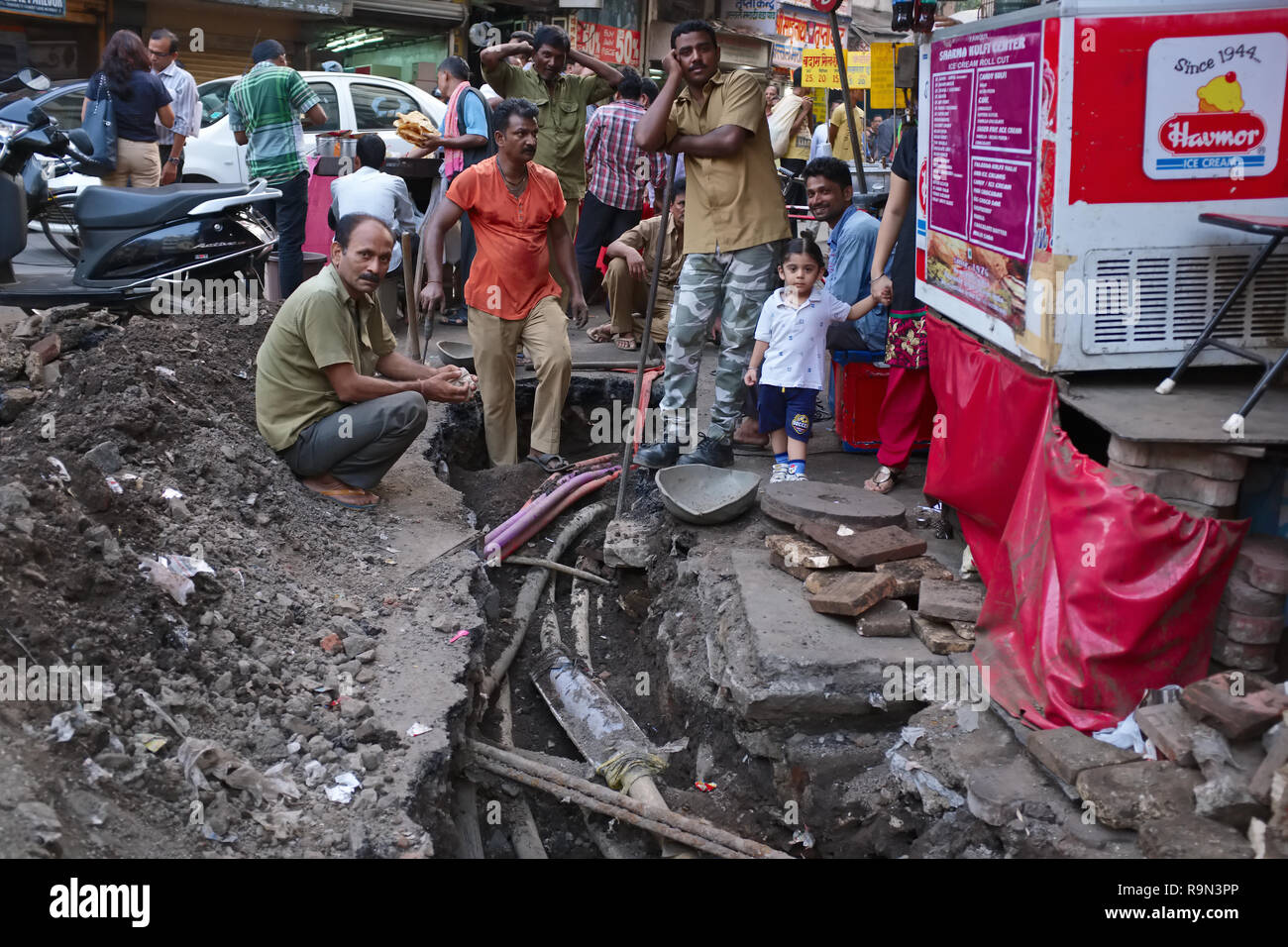 Les employés de la municipalité d'électricité souterrain de fixation des câbles dans une zone commerciale congestionnés à Mumbai, Inde, ajoutant à l'chaos Banque D'Images