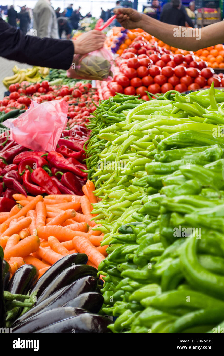 Légumes frais et biologiques sur le marché agricole. Main de l'acheteur et main du vendeur sur fond flou. Banque D'Images