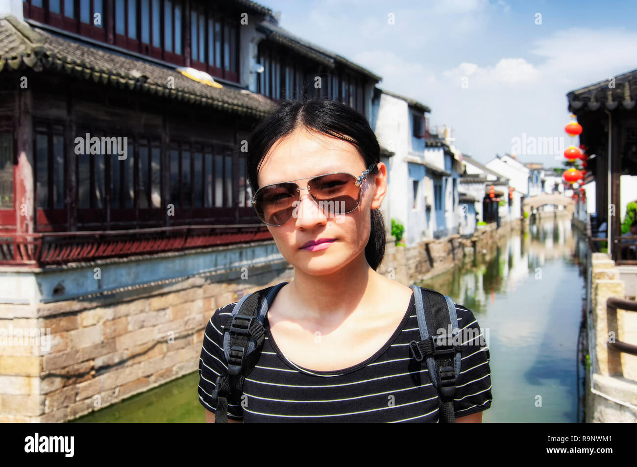 Une femme chinoise portant des lunettes de soleil sur un pont avec les  bâtiments de la ville l'eau Luzhi floues dans l'arrière-plan sur une  journée ensoleillée en Chine Photo Stock - Alamy