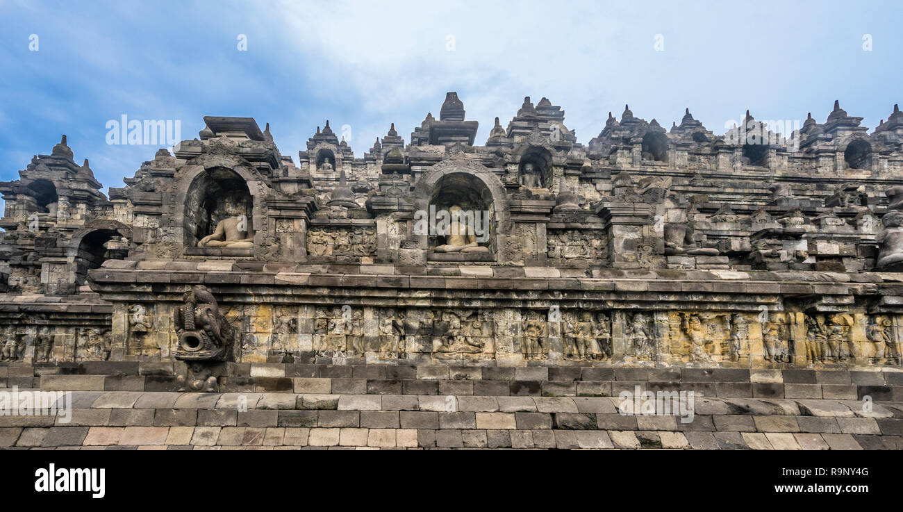 Vue de bas-reliefs des galeries et de nombreuses staues Bouddha logées dans des niches de la base exposée de Borobudur temple bouddhiste, le centre de Java, Indonésie Banque D'Images