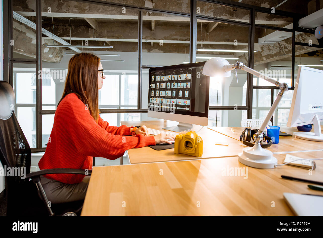 Femme qui travaille comme photographe retouche de photos avec l'ordinateur assis à la place de travail dans l'intérieur de bureau moderne Banque D'Images