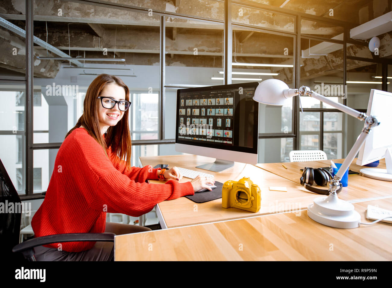 Portrait d'une femme qui travaille comme photographe retouche de photos avec l'ordinateur de bureau à la place de travail dans l'intérieur de bureau moderne Banque D'Images