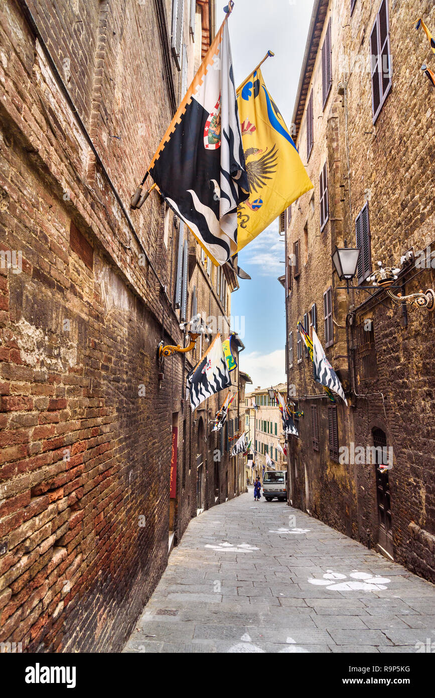 Ruelle médiévale avec des drapeaux Contrade de Sienne, Toscane, Italie. Banque D'Images