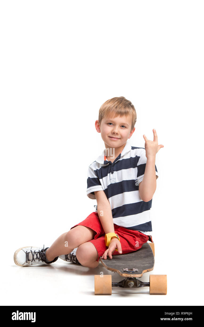 Portrait d'une adorable jeune garçon sur un skateboard isolés contre fond blanc au studio Banque D'Images