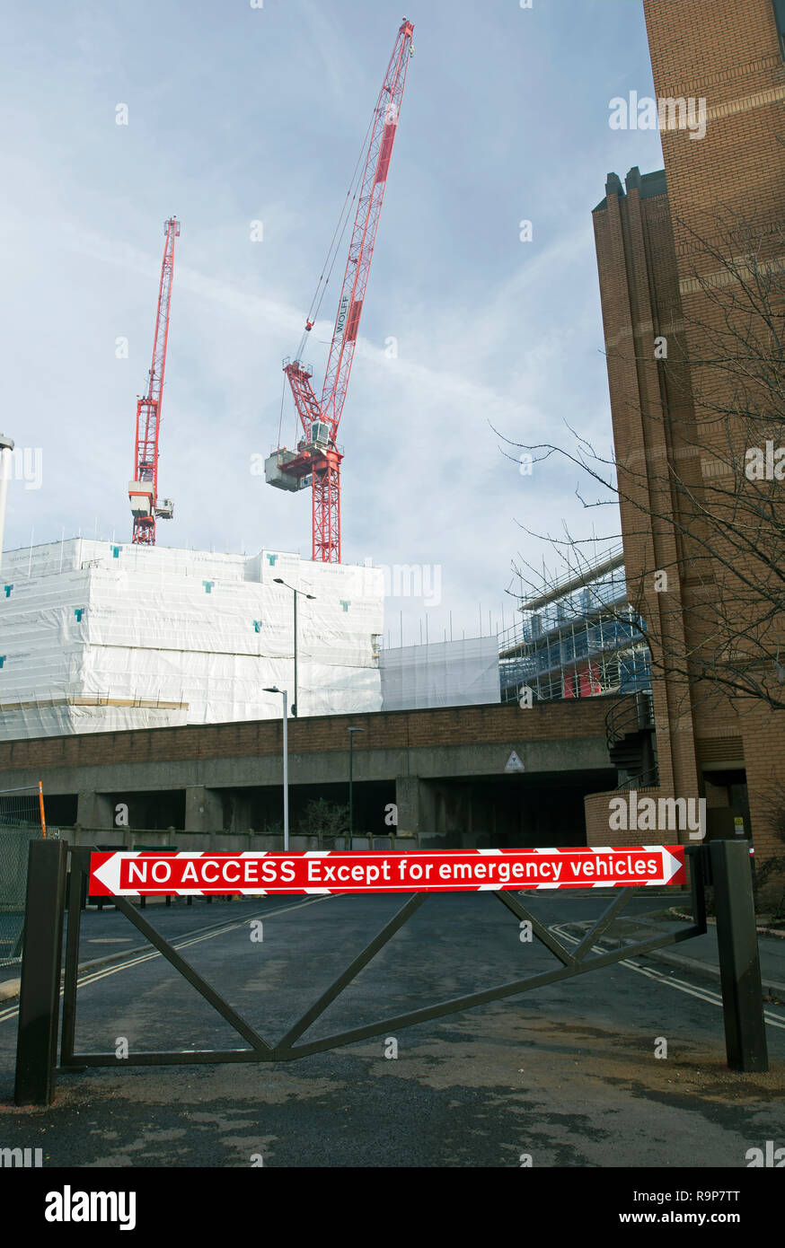 Le rouge et le blanc pas d'accès à l'exception des véhicules d'urgence signe sur un obstacle routier à Twickenham, Middlesex, Angleterre, avec des grues en arrière-plan Banque D'Images