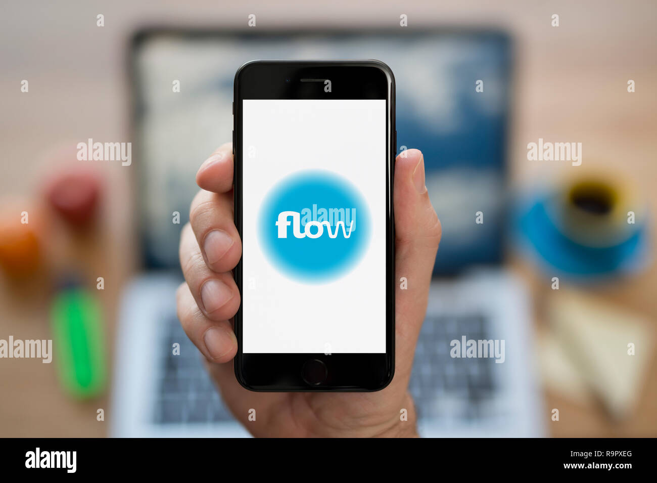 Un homme se penche sur son iPhone qui affiche le logo de l'énergie de flux (usage éditorial uniquement). Banque D'Images