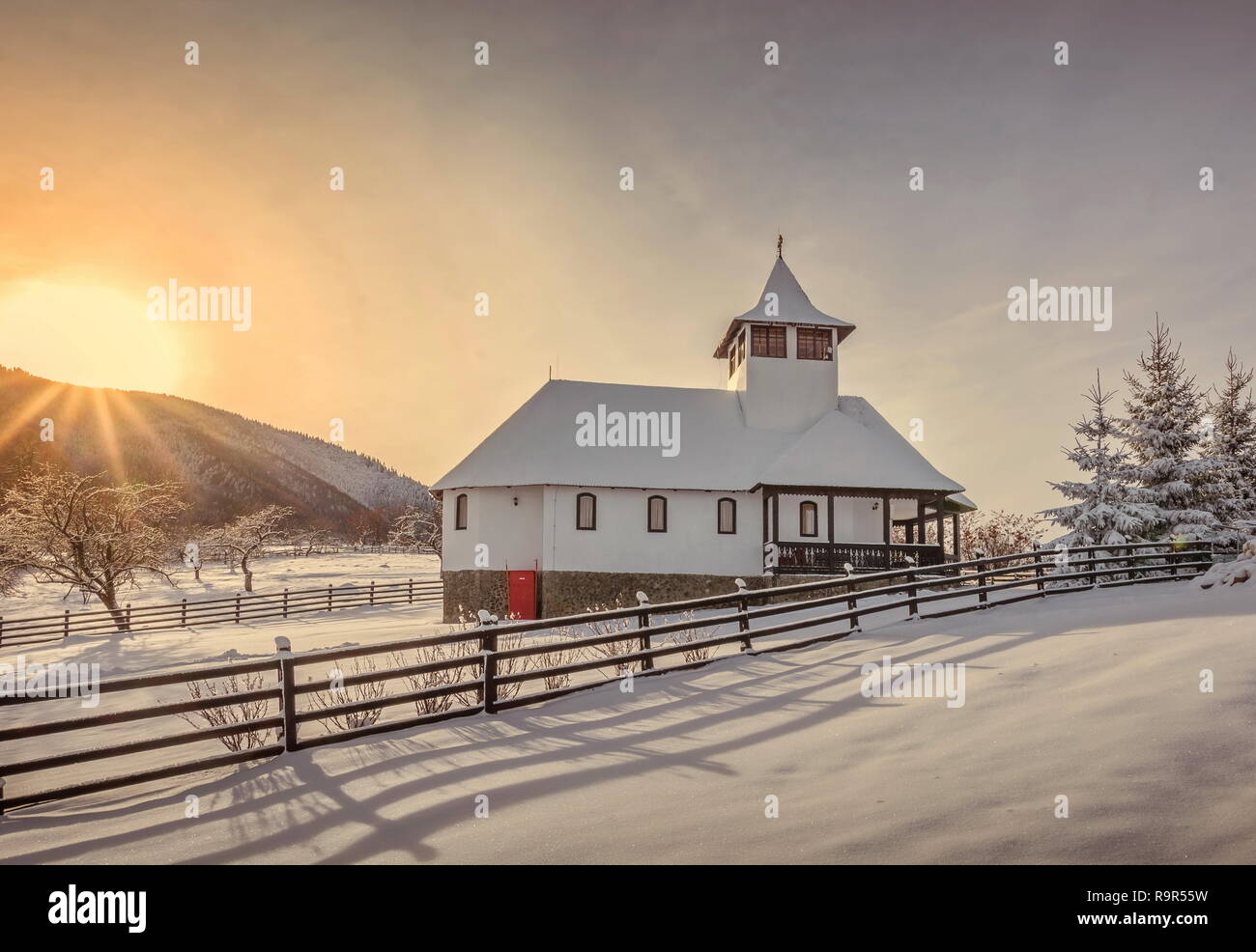 Son Schitul, Simon Brasov, Roumanie - paysage d'hiver au lever du soleil de son église et grange traditionnelle Banque D'Images