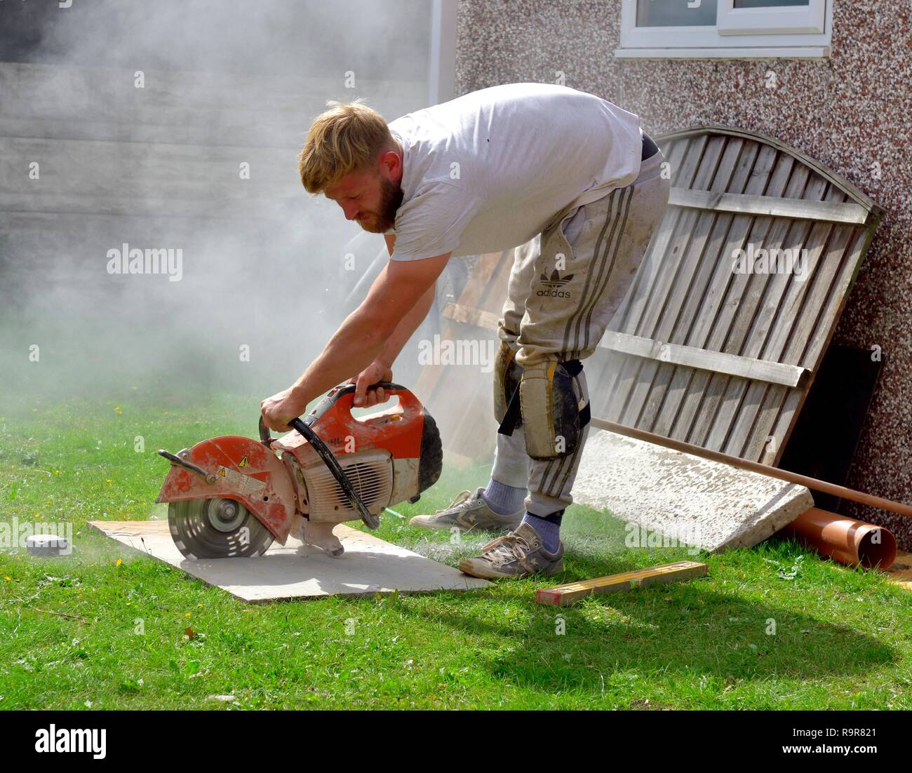 Dalle pavage en pierre d'être coupé avec une scie circulaire par essence uk builder Banque D'Images