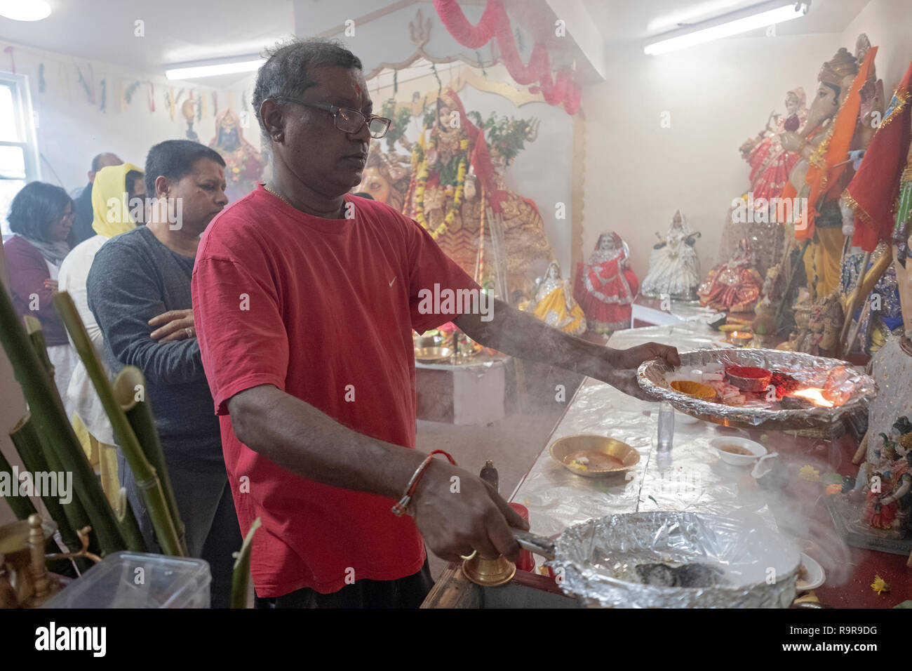 Un hindou pieux man holding de flammes et d'offrandes aux déités dans un temple en Jamaïque, Queens, New York. Banque D'Images