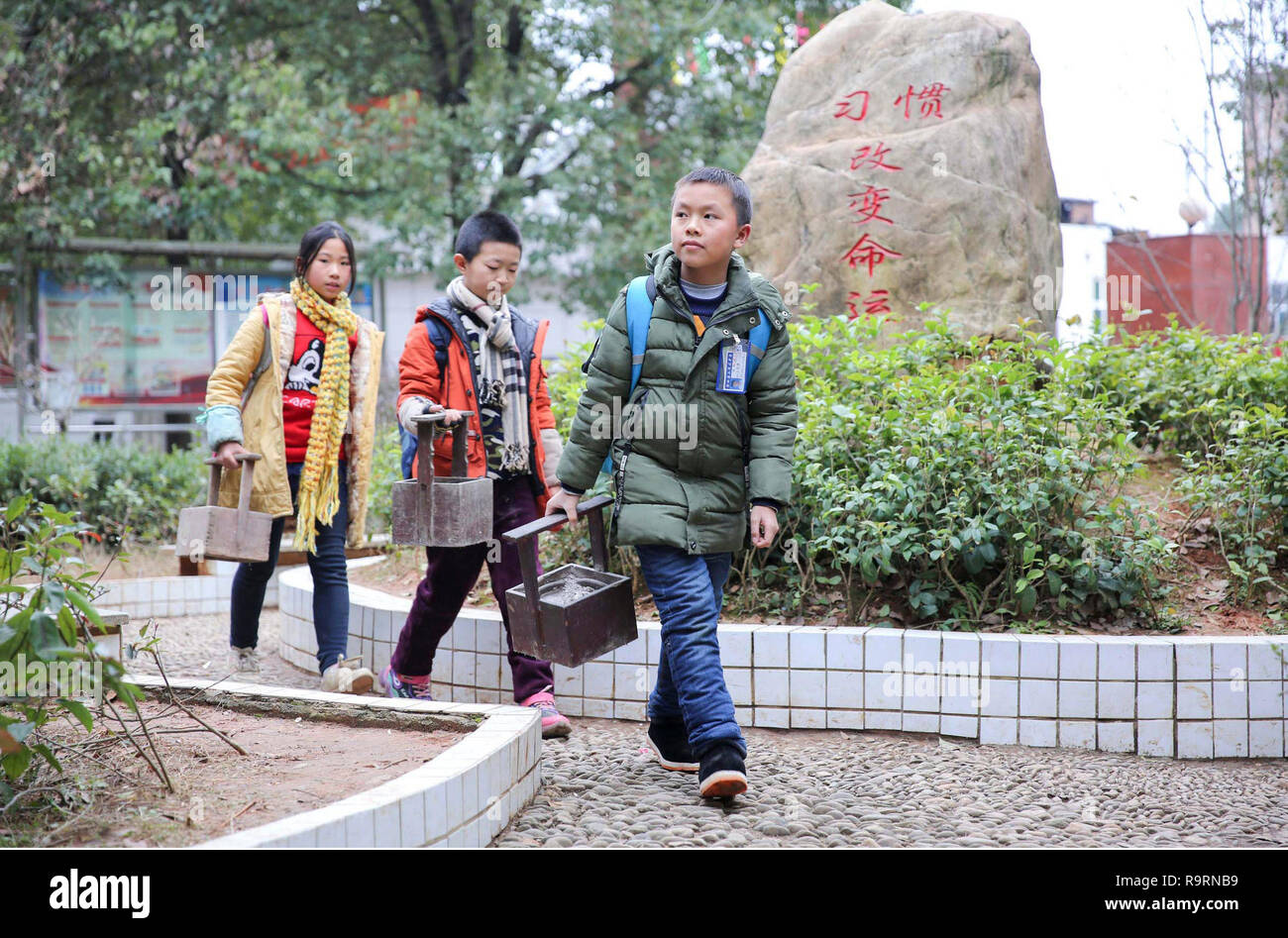 Changsha. 13 Décembre, 2018. Combo photo prise le 13 décembre 2018 montre aux élèves de marcher avec du 'fire' barils pour le chauffage, dans Sangesi Canton de Longhui county dans le centre de la Chine, dans la province de Hunan. Comme la température chute, les gens dans le Hunan utiliser divers appareils de chauffage pour lutter contre la froideur. Credit : Zeng Yong/Xinhua/Alamy Live News Banque D'Images