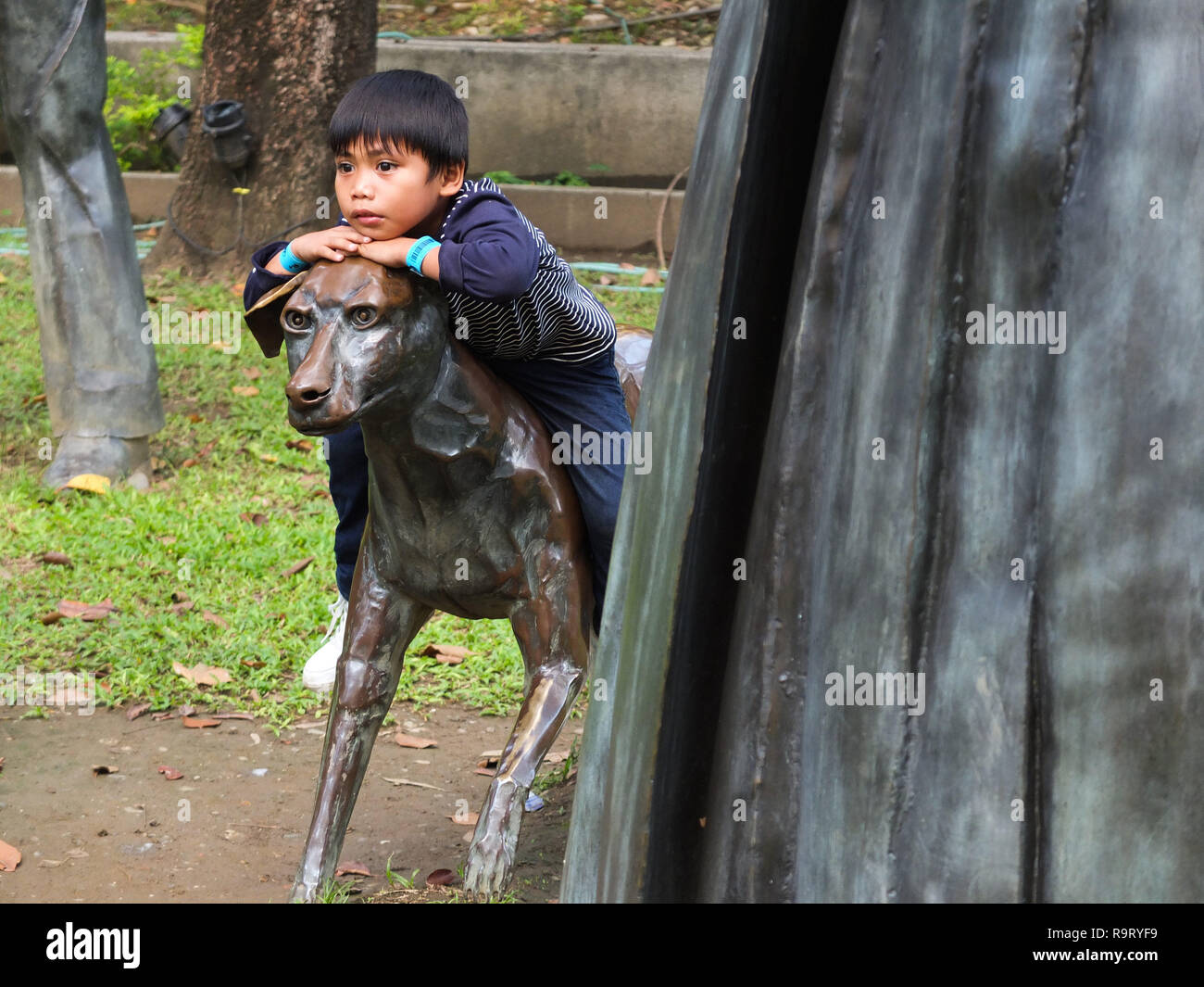 Manille, Philippines. 18 mars, 2012. Un garçon, regarder tout en montant dans une statue en bronze d'un chien dans le parc.L'exécution de l'emplacement de Dr Jose Rizal où vous trouverez des statues en bronze grandeur nature de recréer les derniers moments dramatiques de la vie du héros. Credit : Josefiel Rivera SOPA/Images/ZUMA/Alamy Fil Live News Banque D'Images