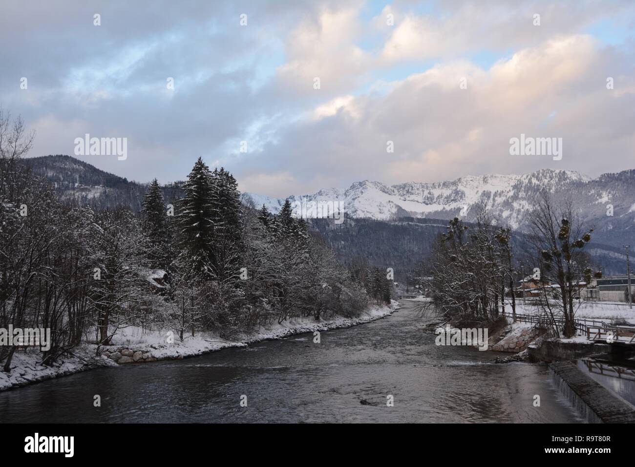 Bad Goisern, rivière vue d'hiver. Montagnes de neige et ciel dramatique à l'arrière-plan. Hallstatt, Autriche. Banque D'Images