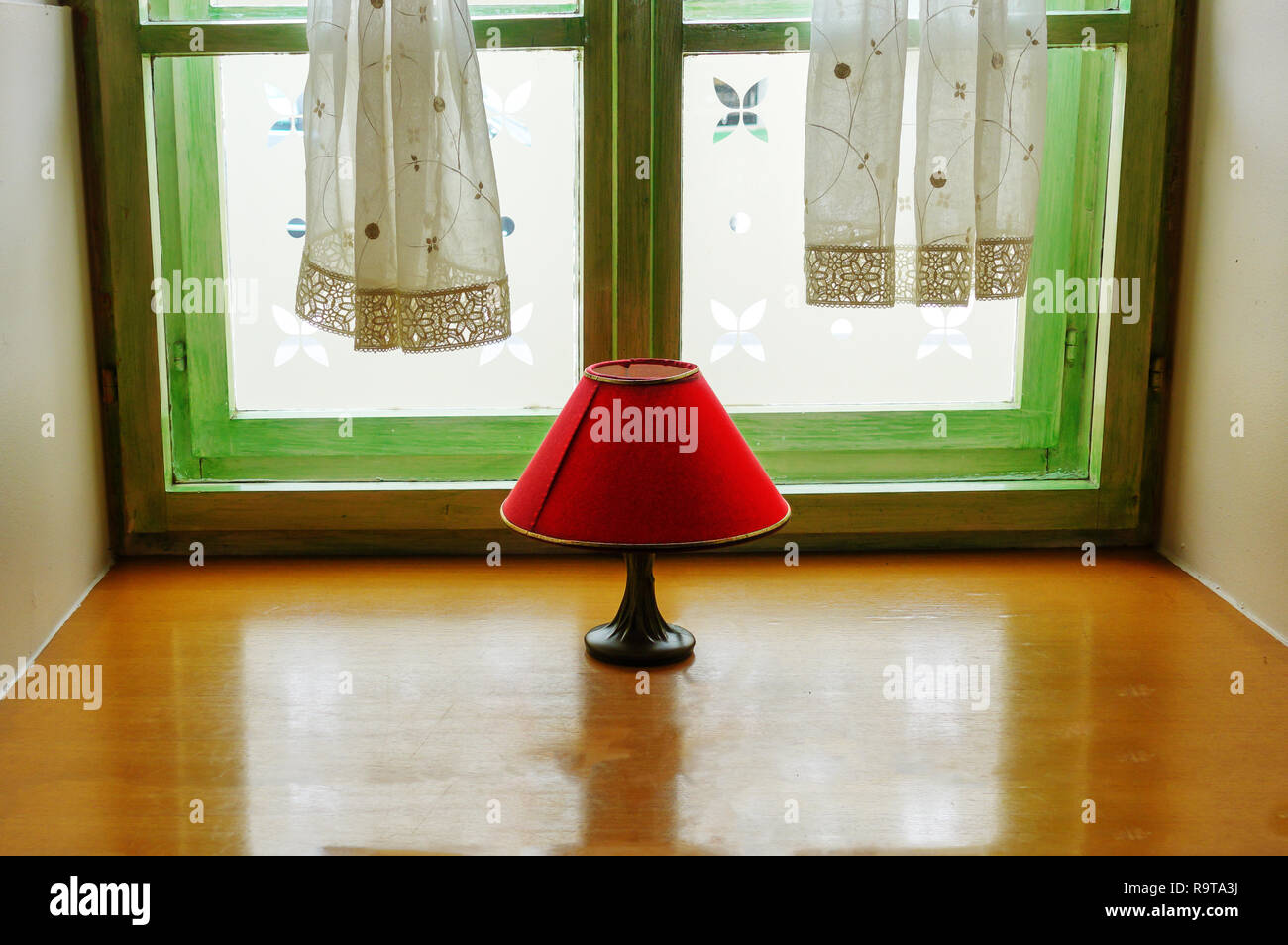 Vintage lampe rouge avec de l'ombre sur la fenêtre, scène d'intérieur intime, reflet dans la tablette de bois, décoration design et concept Banque D'Images