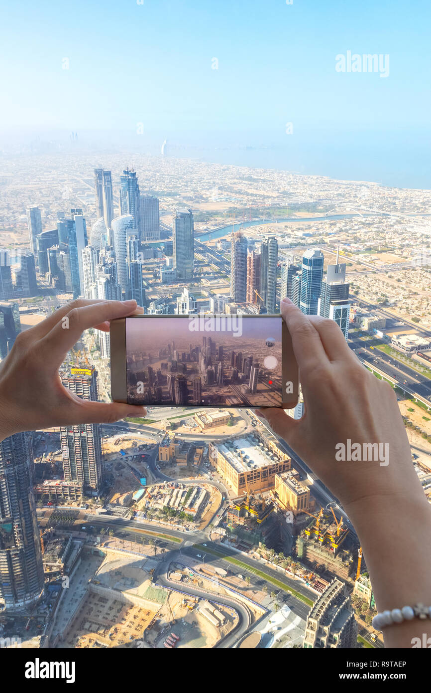 Gros plan du touriste hand taking photo de la ville de Dubaï avec l'appareil photo du smartphone à partir de la tour Burj Khalifa. Girl taking picture with mobile phone sur holi Banque D'Images