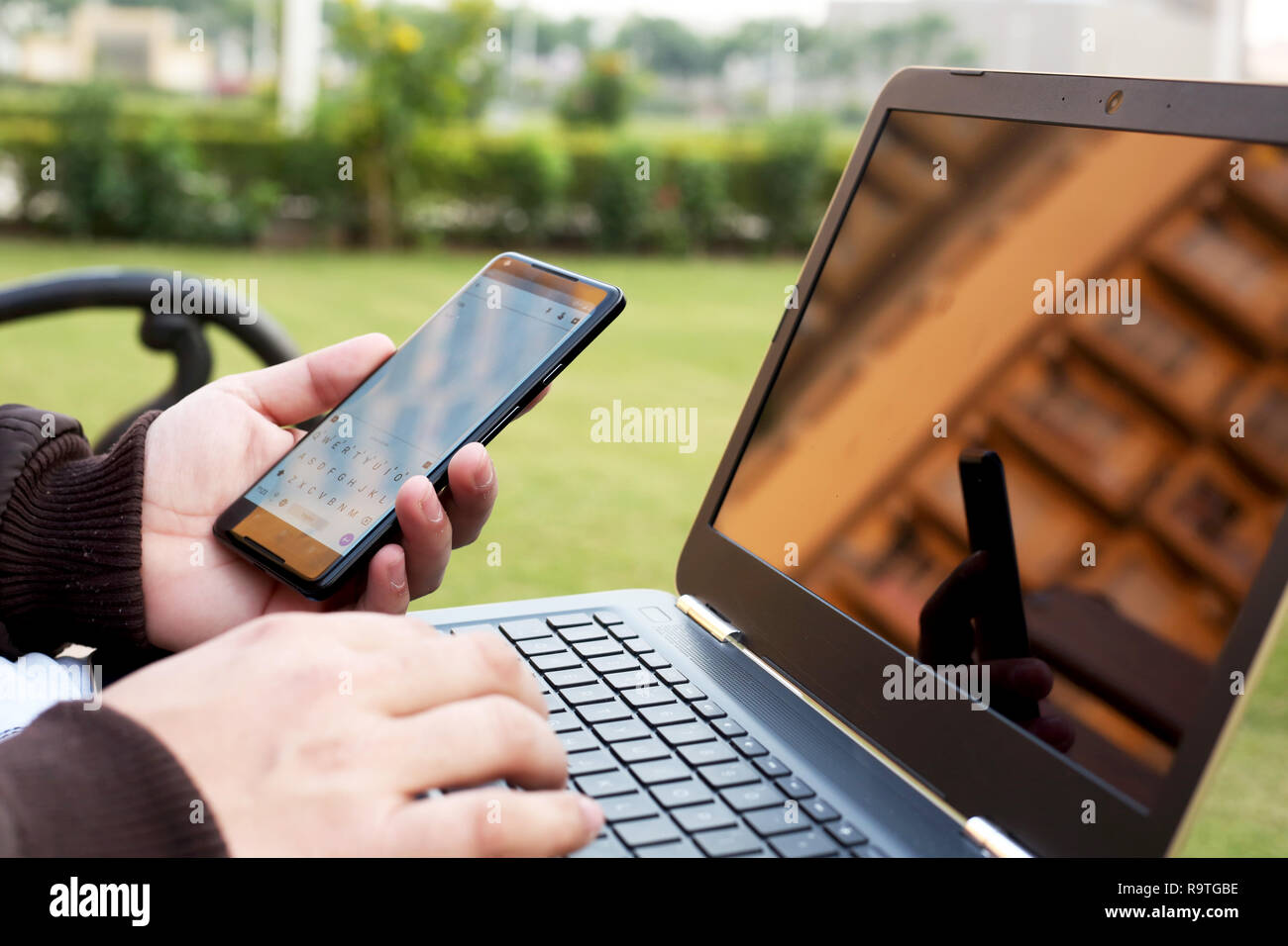L'homme est holding smartphone dans la main avec l'ordinateur portable. Banque D'Images