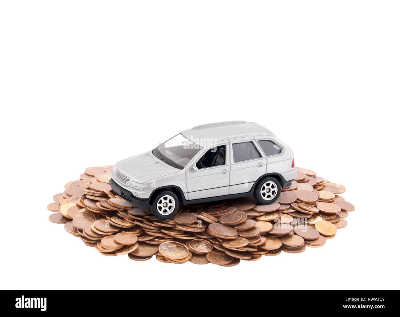 Petite voiture d'argent sur un tas de pièces isolées sur fond blanc Banque D'Images