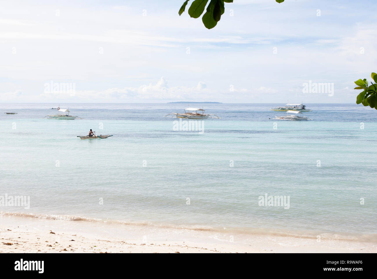 Blue ocean exotiques avec des bateaux et l'homme à pagayer à Dumaluan Beach, l'île de Panglao, Bohol, Visayas, Philippines, Asie du Sud, Asie Banque D'Images