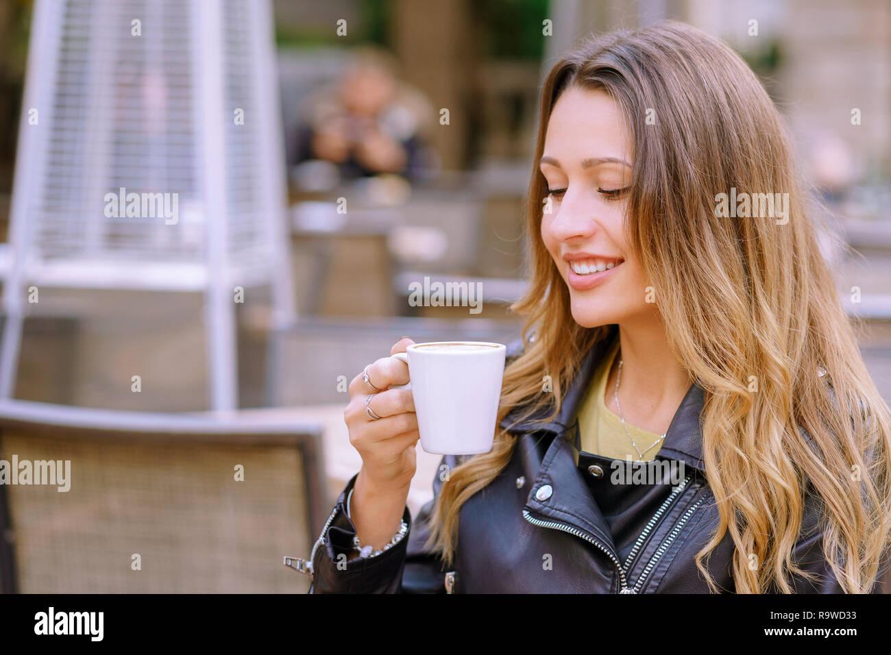 Close up portrait of girl holding une boisson chaude tout en restant assis sur fond flou de outdoor cafe Banque D'Images