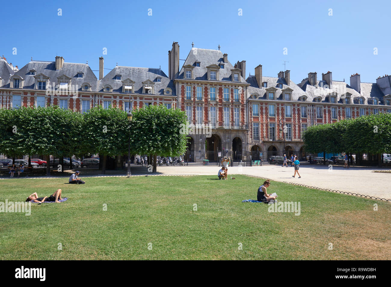PARIS, FRANCE - Le 6 juillet 2018 : Place des Vosges d'anciens bâtiments et des gens sur l'herbe dans un beau jour d'été, ciel bleu clair à Paris Banque D'Images