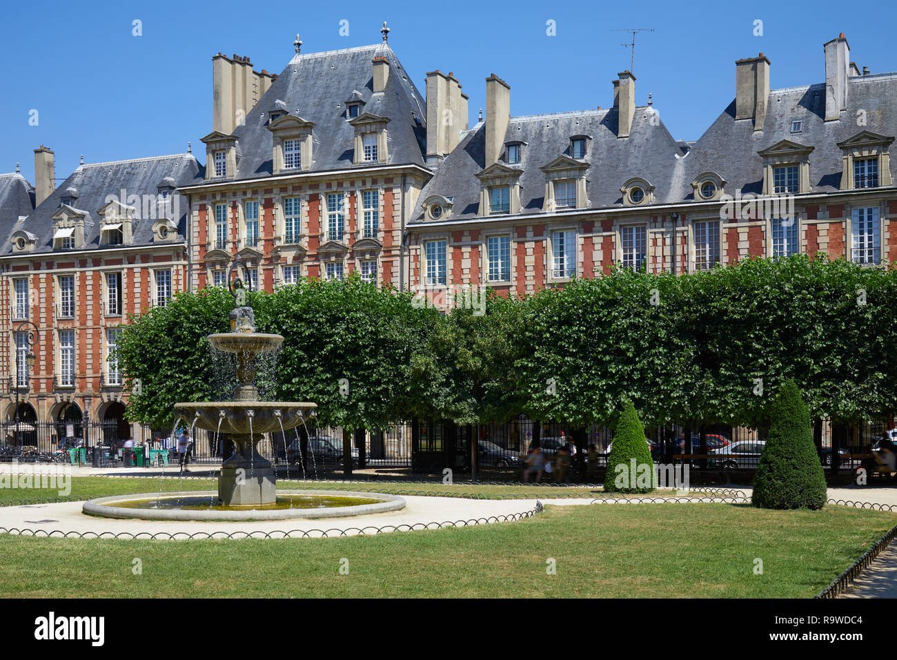La Place des Vosges, la façade rouge bâtiments et jardin à Paris dans un beau jour d'été, ciel bleu clair Banque D'Images