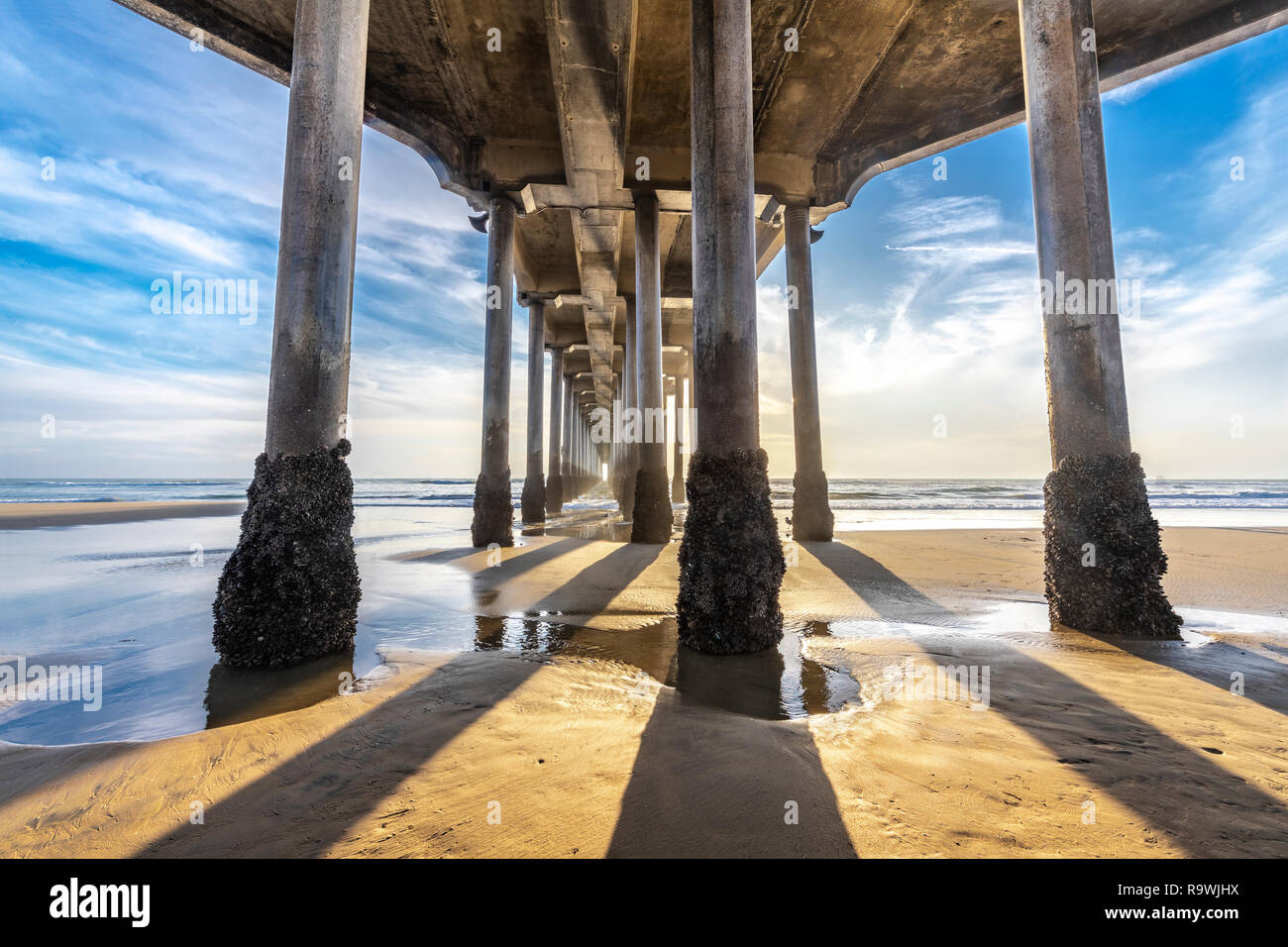 La face inférieure de l'Huntington Beach pier en Californie du sud, tourné pendant le coucher du soleil jette de longues ombres sur le sable doré. Banque D'Images
