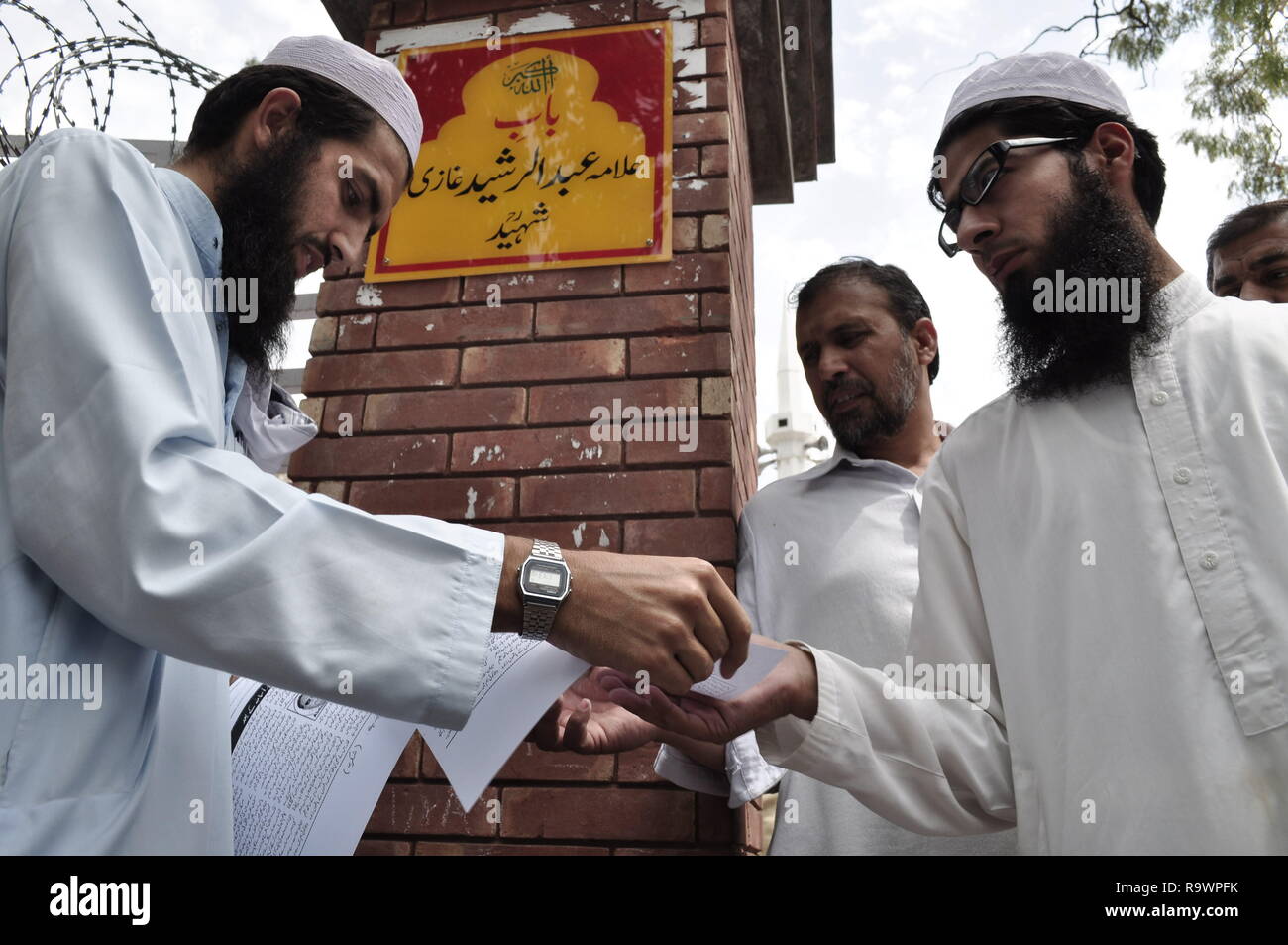 Un homme distribue des dépliants à l'extérieur de la mosquée Rouge à Islamabad, également connu sous le nom de laal masjid avant jummah prières. Banque D'Images