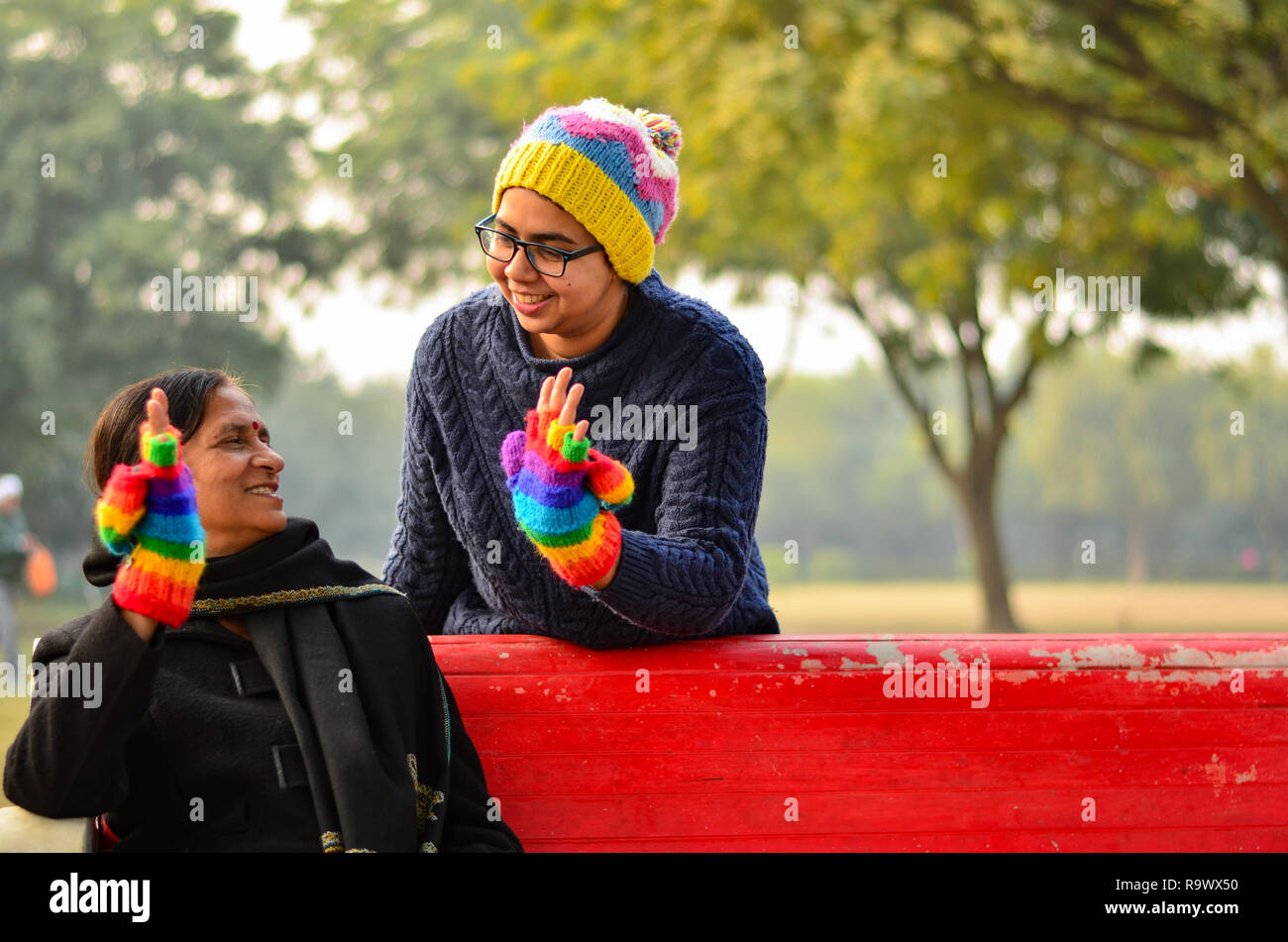 Heureux à la jeune femme avec sa mère cinq haut-ing hi5 avec même des gants colorés dans un parc à New Delhi, Inde Banque D'Images