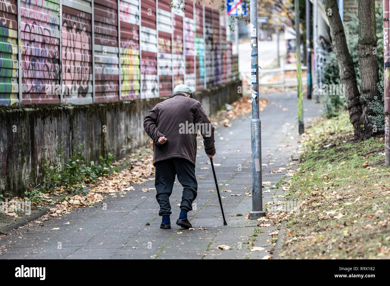 Vieil homme marche lentement, appuyé sur un bâton de marche, Banque D'Images