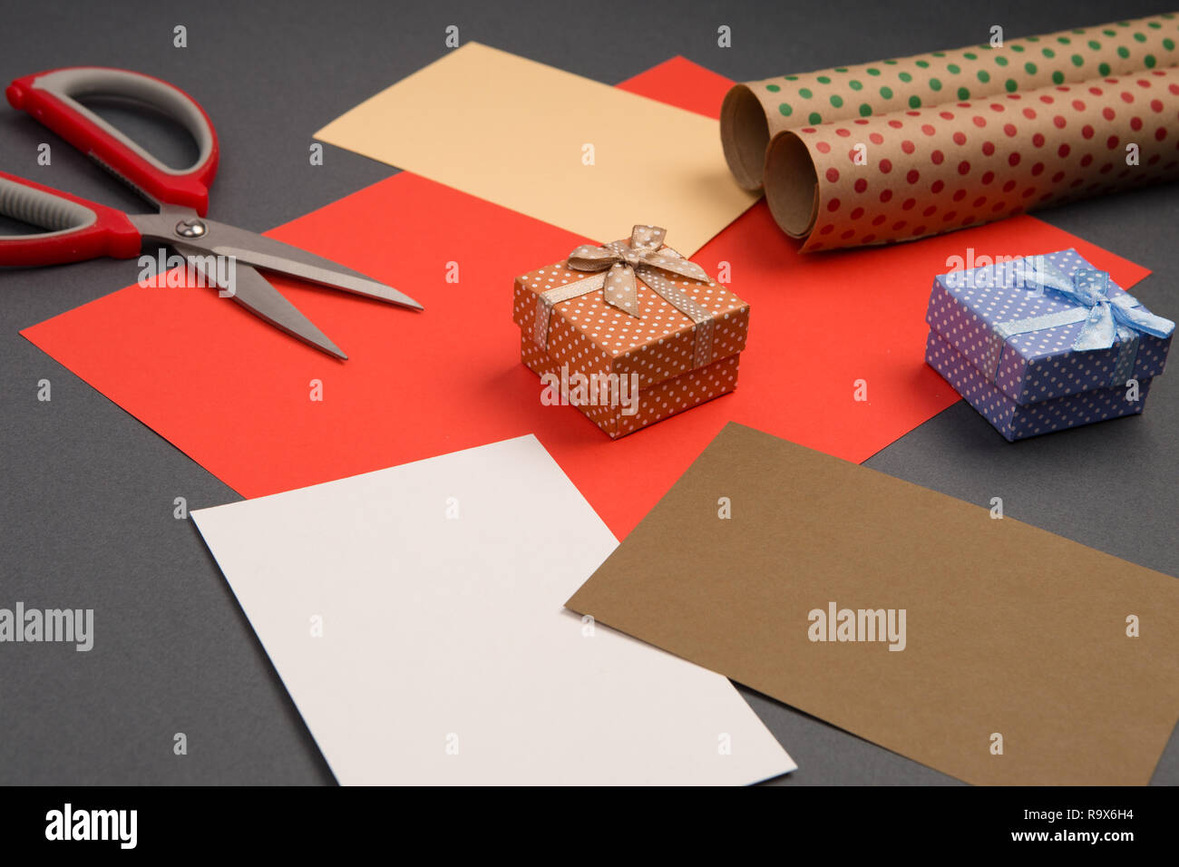Concept de célébration - Coffrets cadeaux à pois blancs, d'emballage, papier couleur et ciseaux sur fond gris Banque D'Images