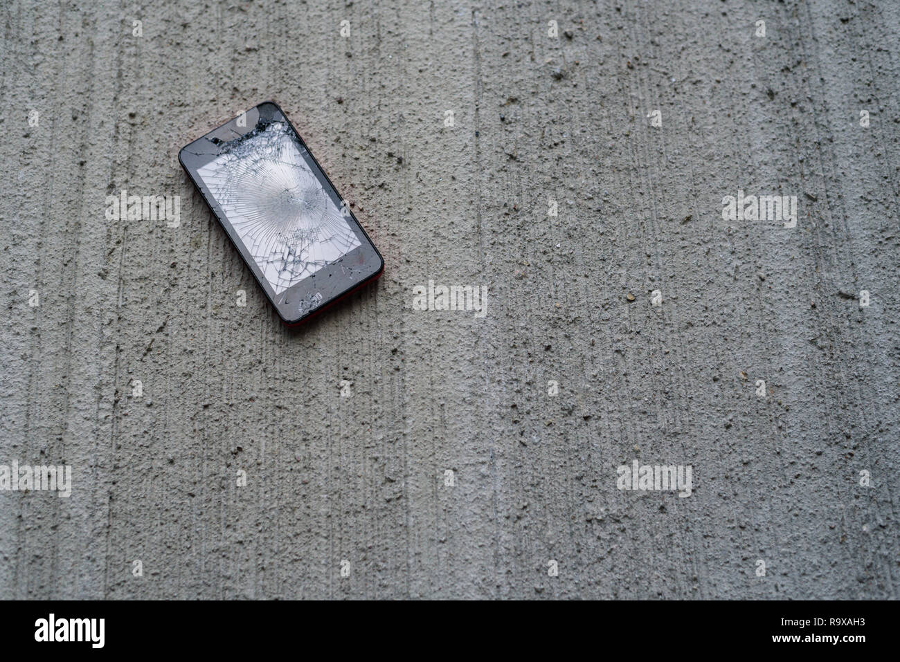 Téléphone avec écran cassé sur fond de béton Banque D'Images