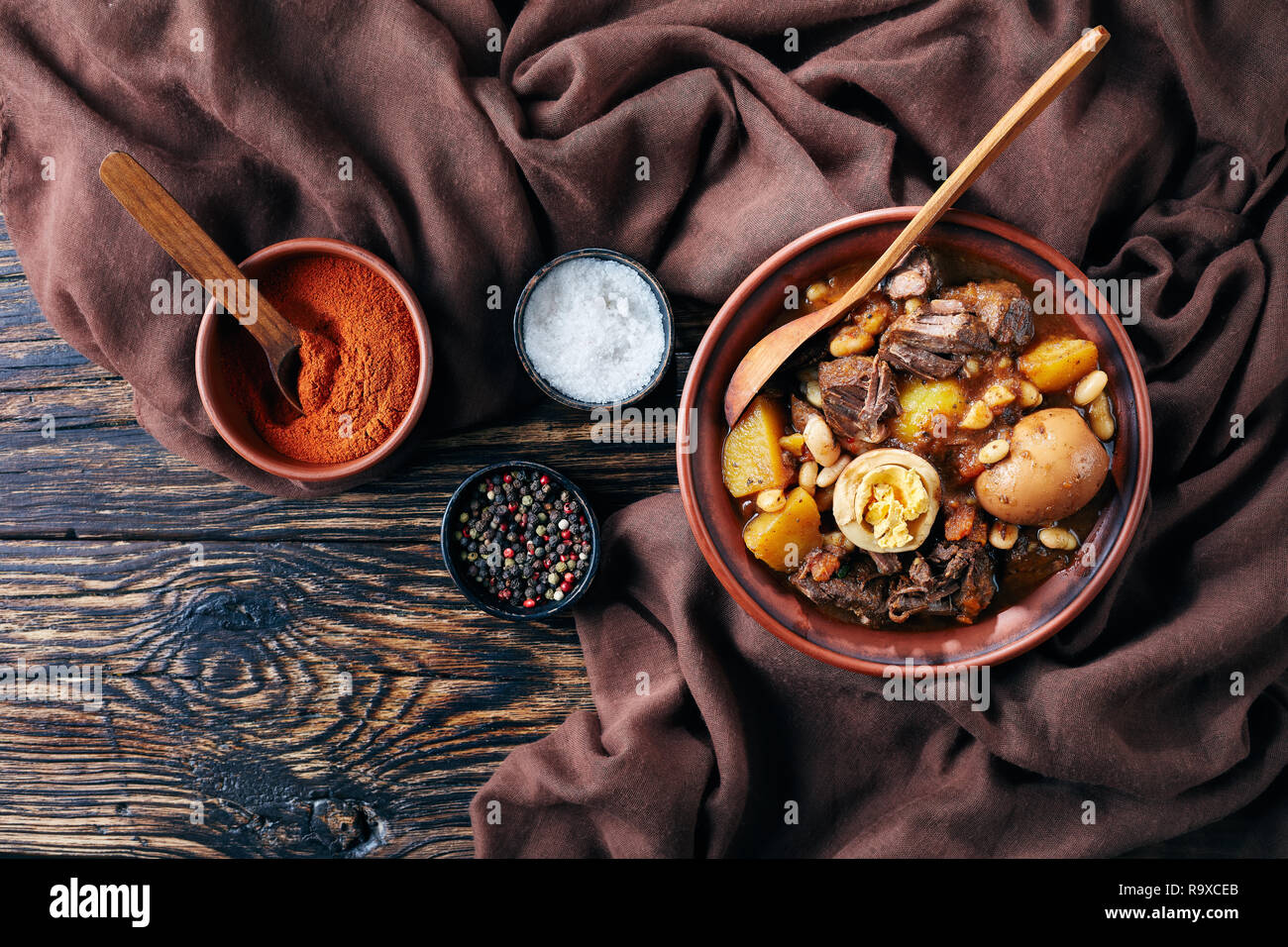 Hamin Tcholent juif traditionnel - plat principal pour le repas de chabbat, lent boeuf cuit avec des pommes de terre, les haricots et les oeufs dans un bol brun sur un onglet en bois rustique Banque D'Images