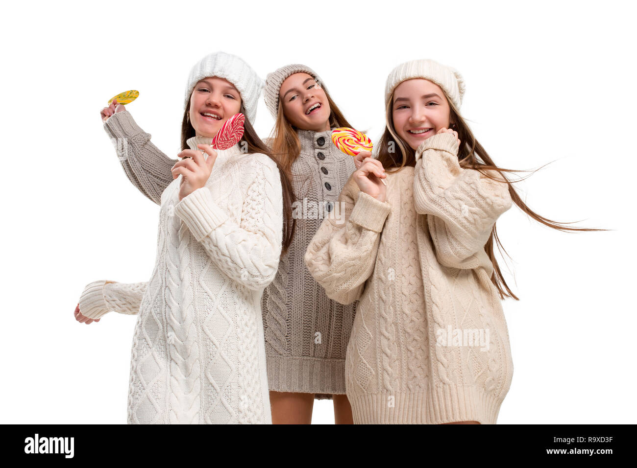 Portrait of cute little kids in élégant chandail tricoté avec des bonbons à la caméra et au sourire contre mur blanc studio. Kids Fashion Concept Banque D'Images