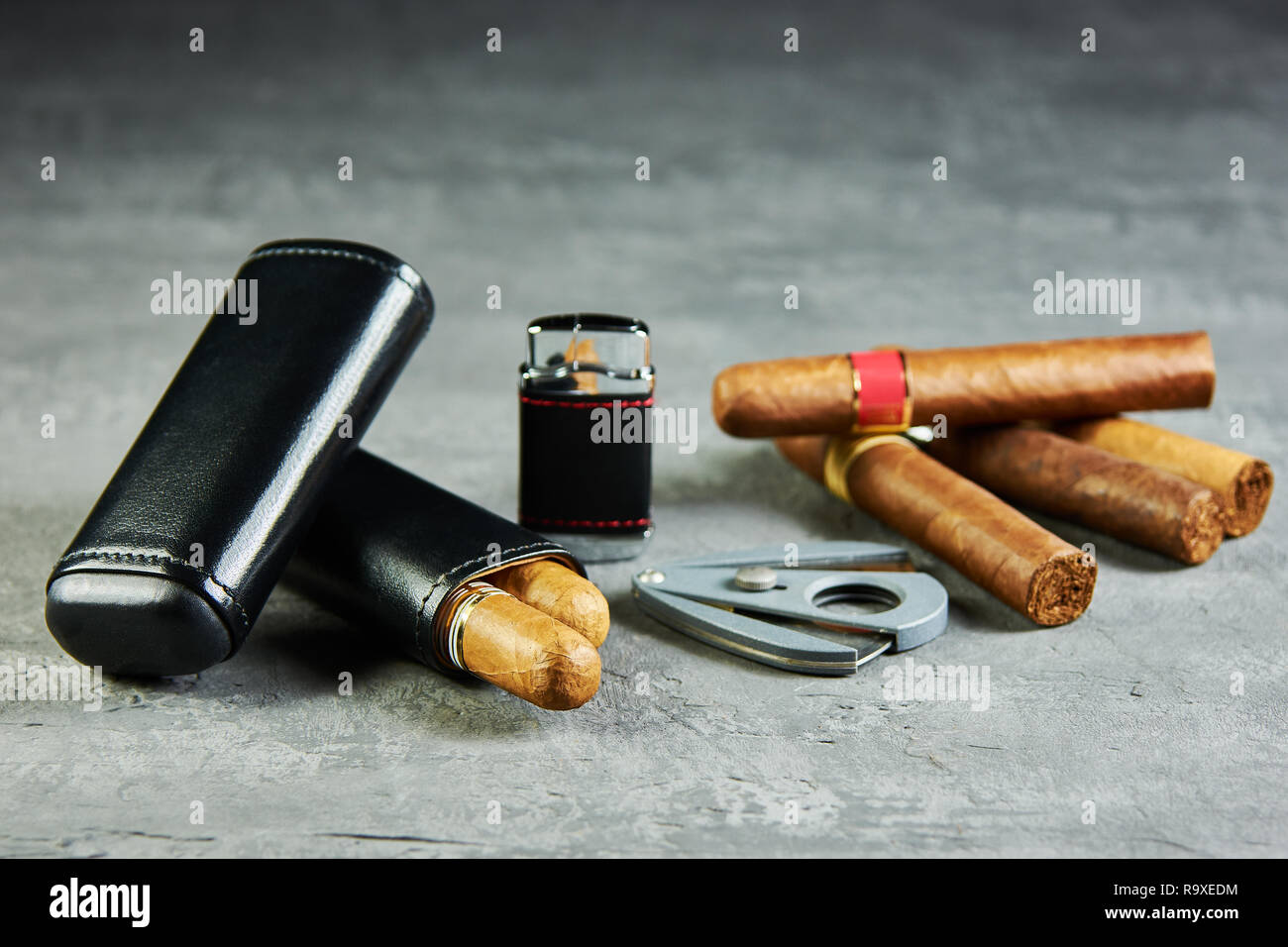 Six cigares cubains sur une table en pierre avec un briquet, cutter et un étui en cuir. Banque D'Images