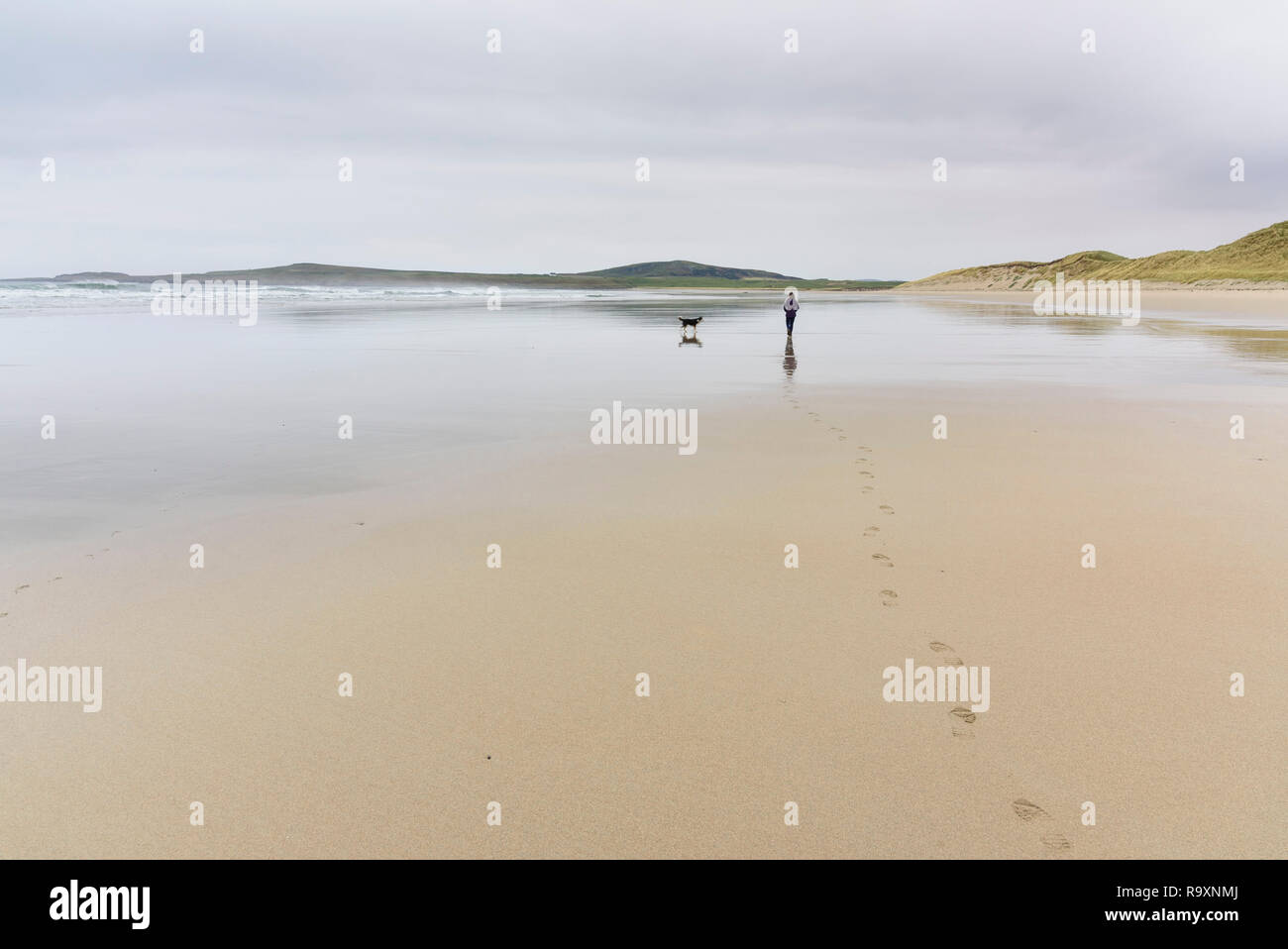 Femme promener son chien le long de Machir Bay, plage de Traigh Mhachir, Rhinns d'Islay, Hébrides intérieures, ARGYLL & BUTE, Ecosse Banque D'Images