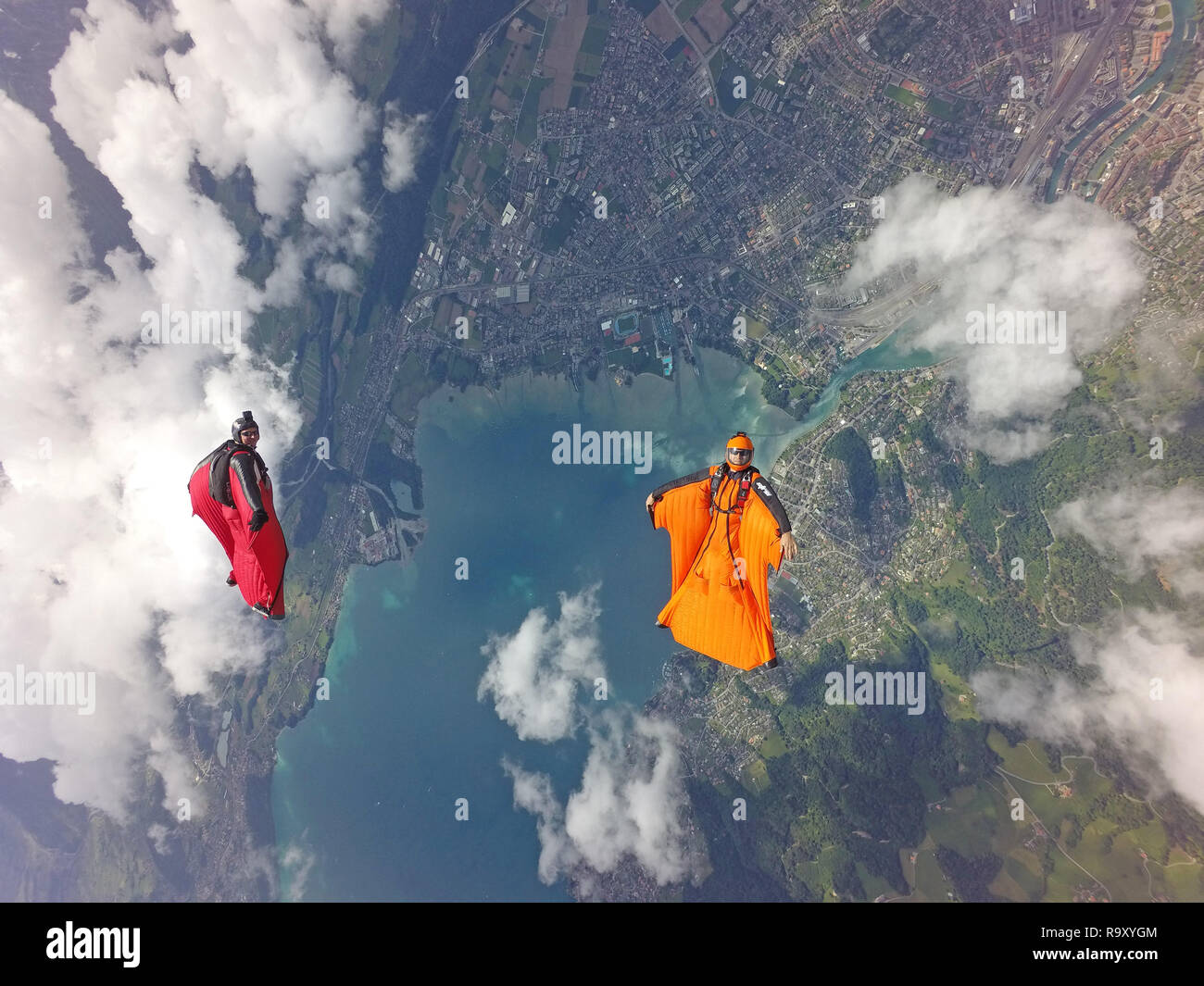 Ces deux pilotes sont wingsuit s'amuser ensemble en volant en une formation autour des nuages. Ils sourient à chaque autre et profiter de l'heure dans le ciel. Banque D'Images