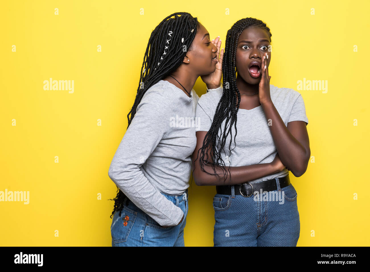 Portrait de deux jeunes femmes africaines secrets partage sur fond jaune isolé Banque D'Images